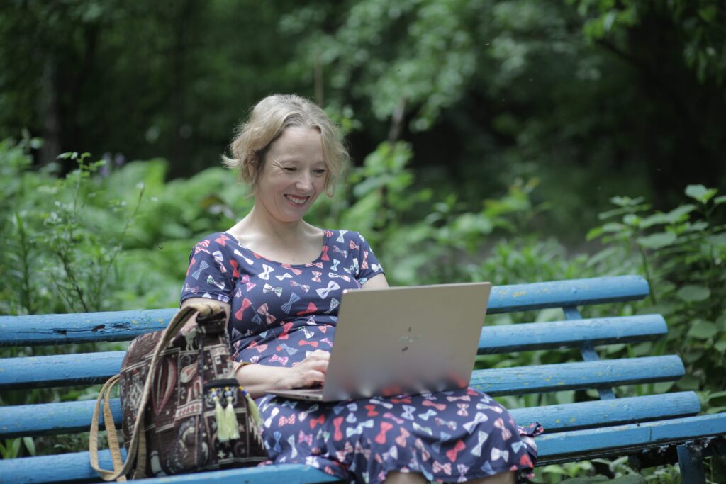 Woman sitting on a park bench with a laptop